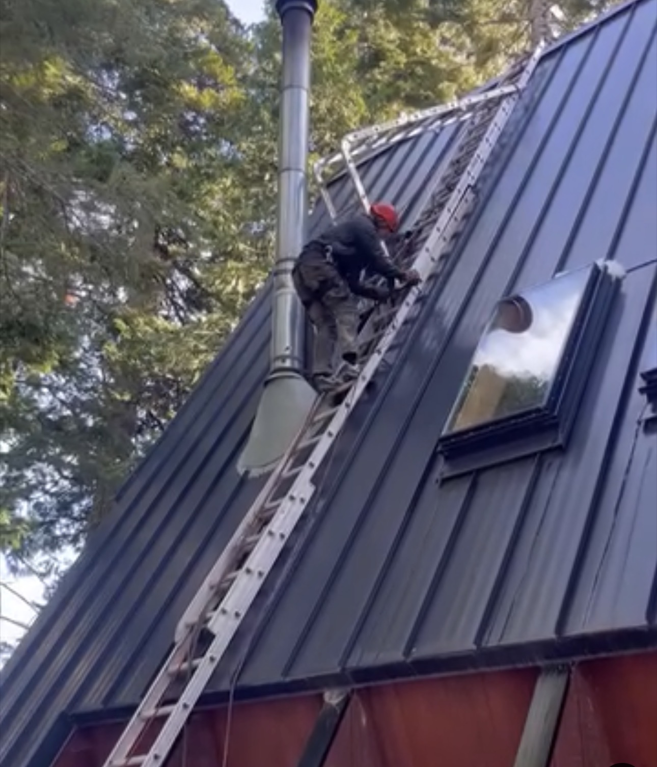 Billy working on a high angle metal roof with a ladder