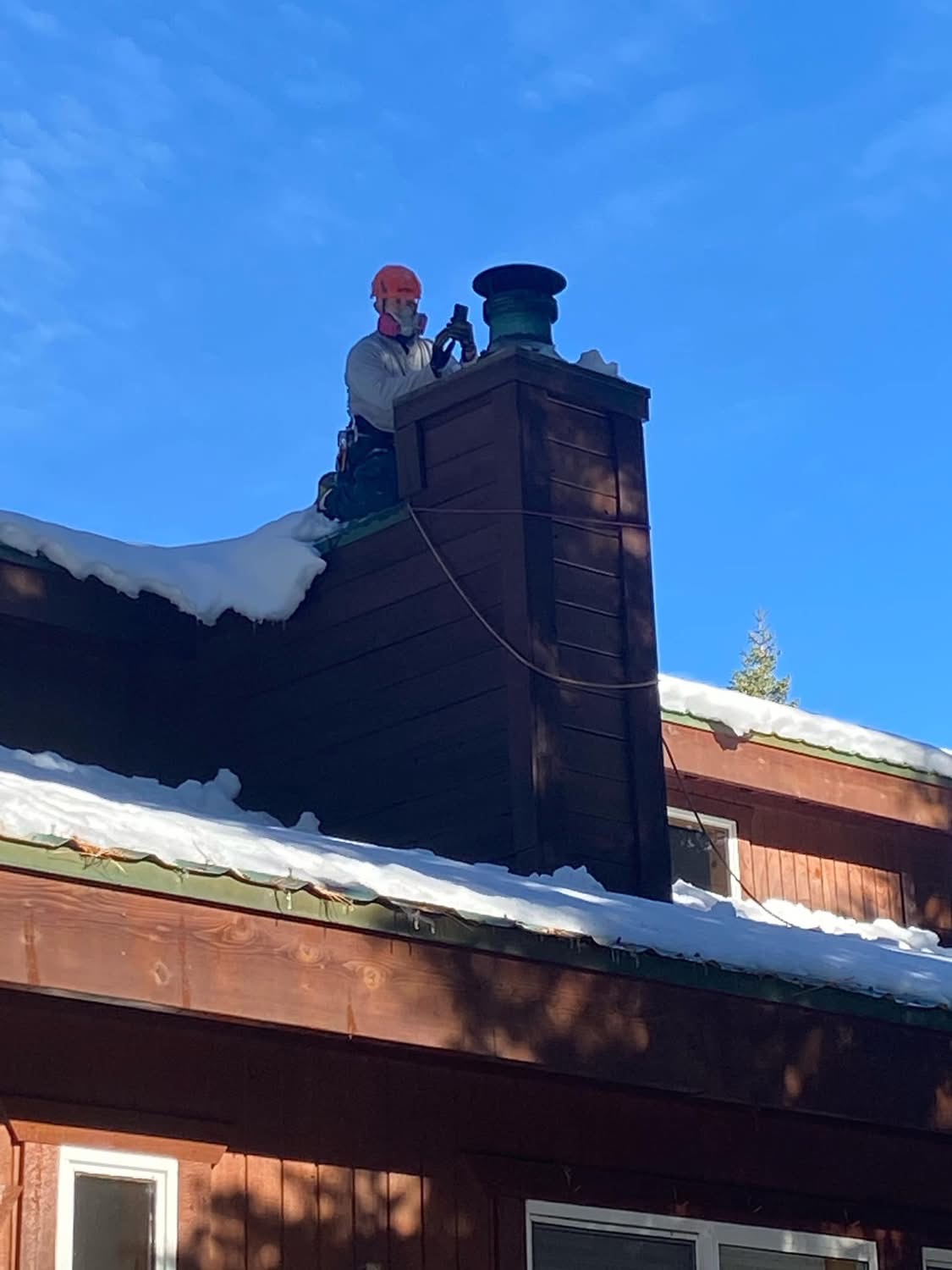 Billy cleaning a chimney on a snowy mountain home